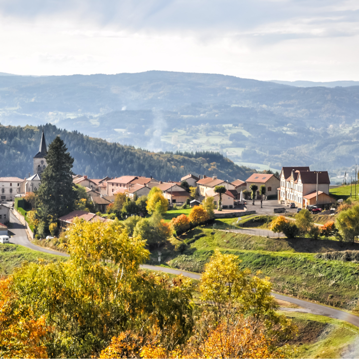 A rolling countryside village surrounded by green hills and mountain views in rural France.