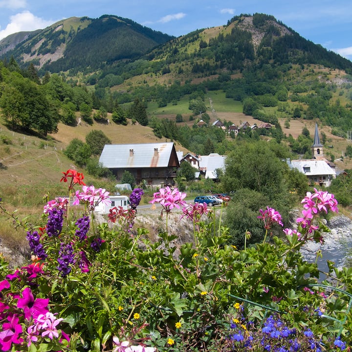 Mountain village surrounded by rolling green hills and wildflowers in the French countryside.
