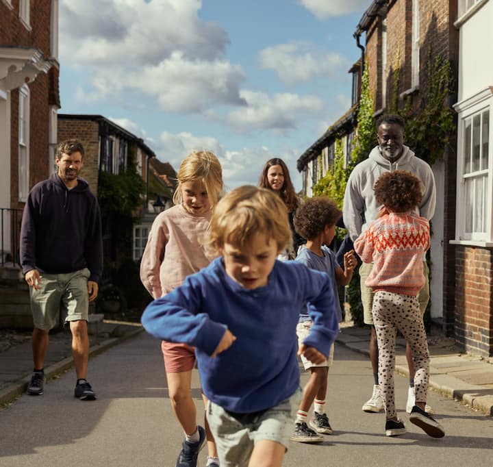 A photo of children playing  as neighbors gather on the cobblestone street in a quiet neighborhood.
