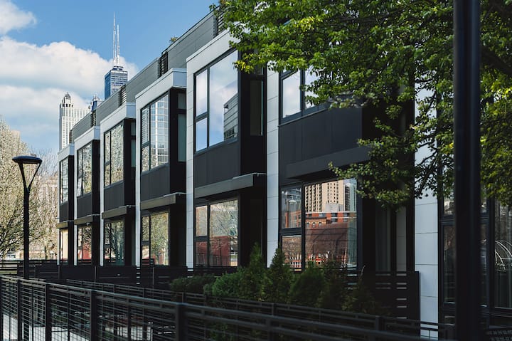 A photo of a modern housing complex with patios and greenery outside each unit.