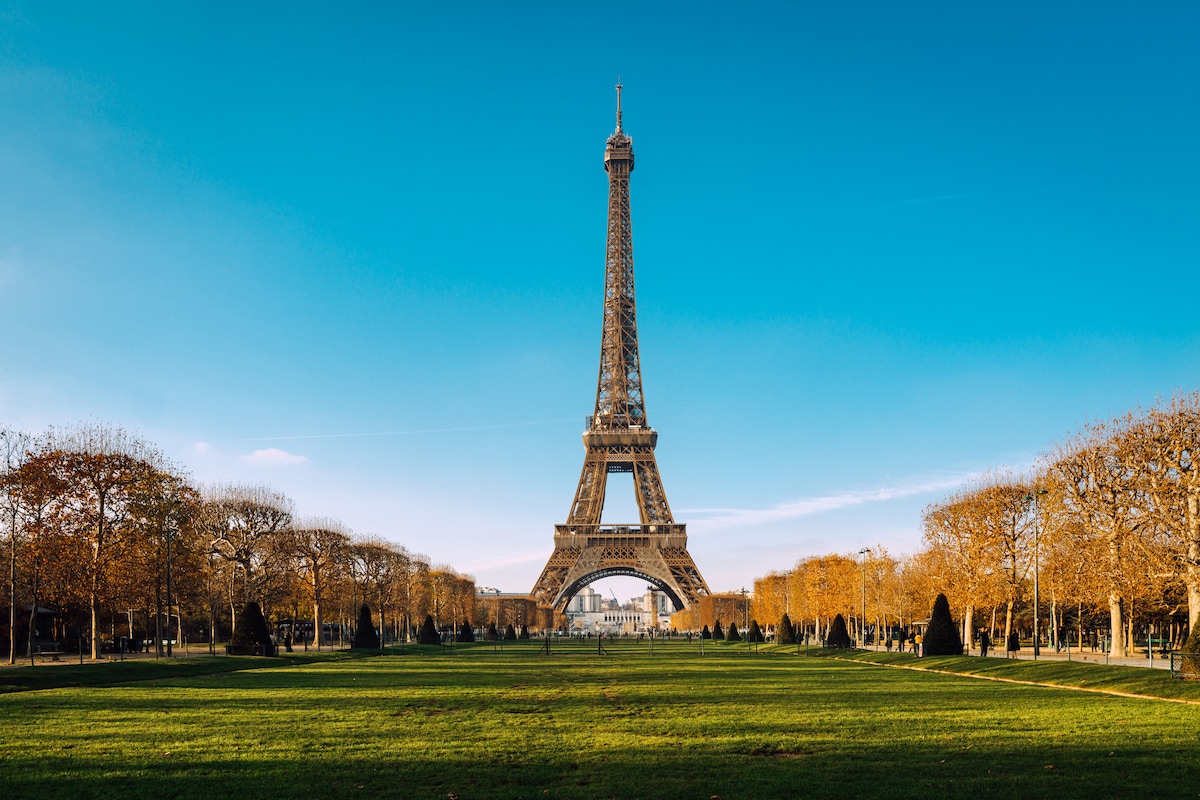 Eiffel Tower rising over a green lawn in Paris under a clear blue sky