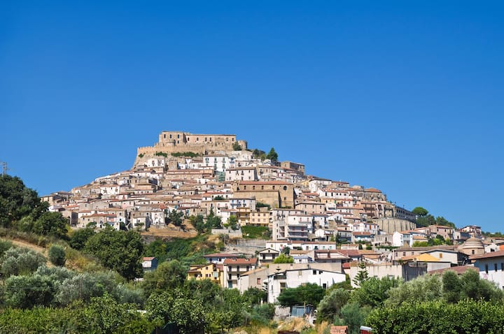 Borgo collinare italiano con case ravvicinate e castello in cima, esempio di piccolo comune senza hotel.
