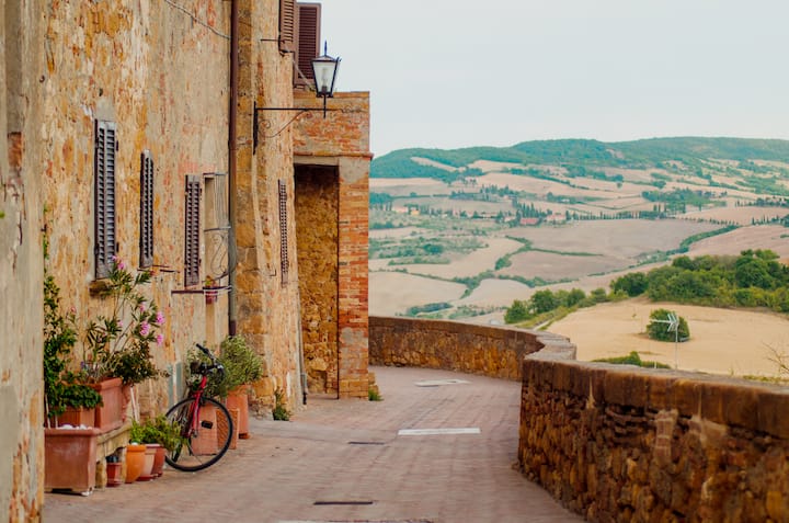 Quiet hilltop village lane overlooking rolling countryside and farmland, suggesting tourism beyond major city centers