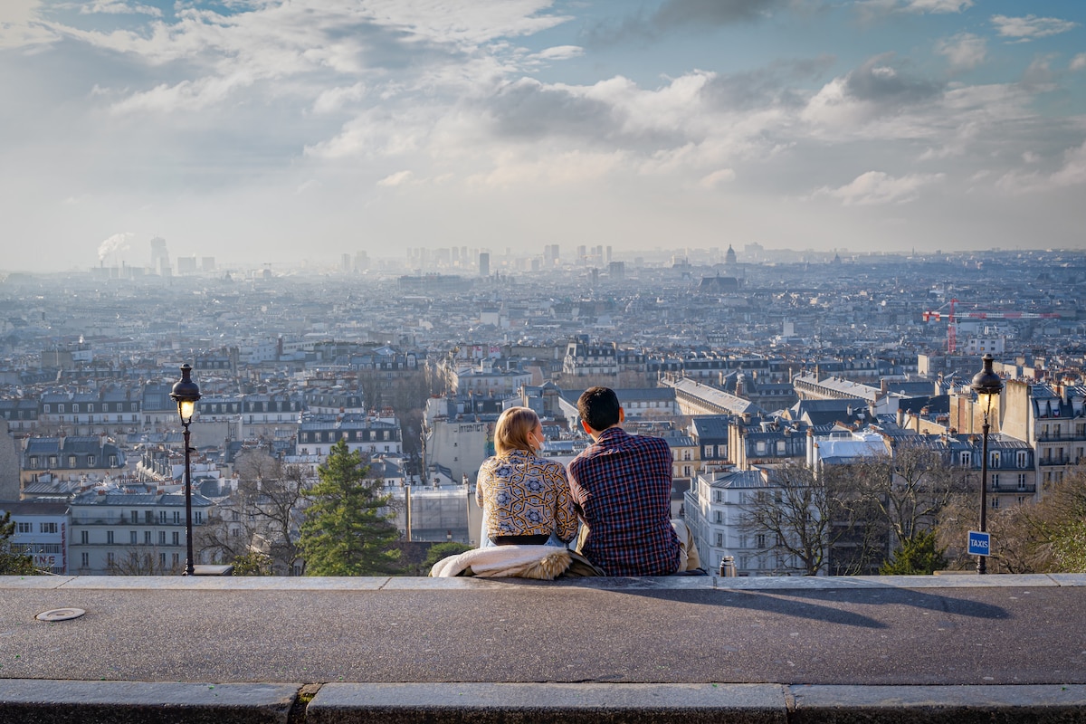 Romantic couple resting side by side above Paris, enjoying the expansive city view.