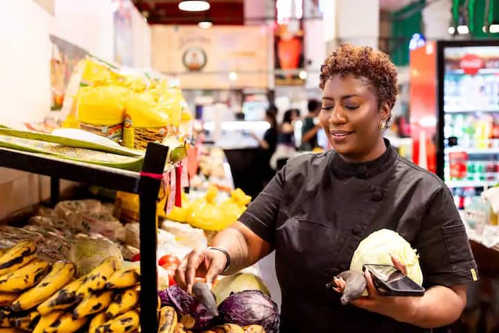 Host selecting fresh produce at Grand Central Market in downtown Los Angeles for an Airbnb Experience food tour.