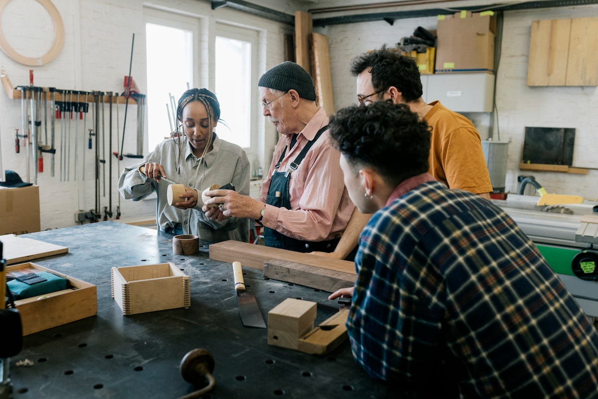 Guests gathered around a workbench learning woodworking together in a hands-on workshop