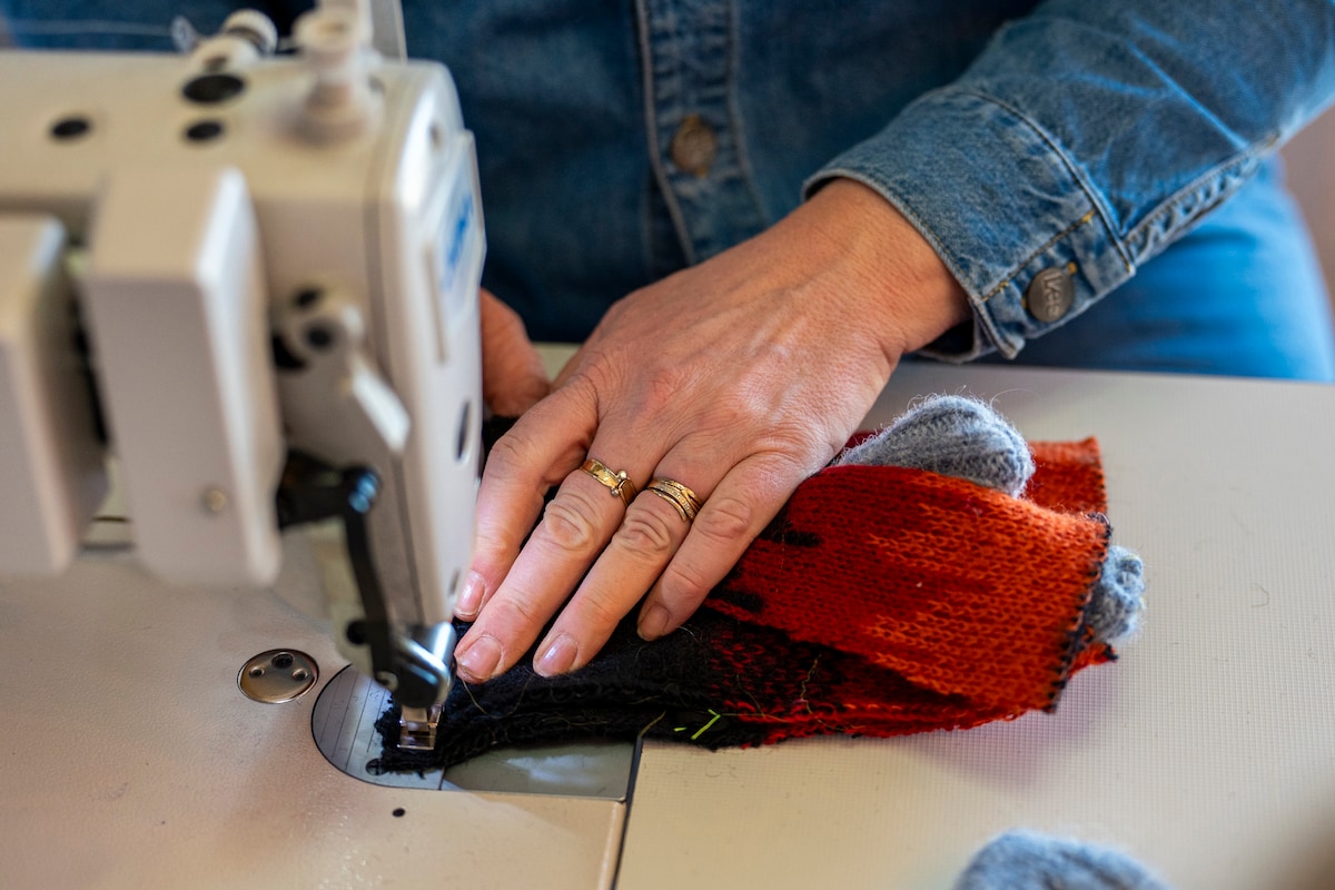 Hands sewing colorful knit fabric on a machine during a textile workshop activity