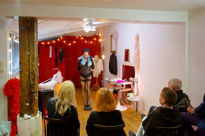 Performer in a cozy cabaret-style room entertaining a small seated audience at night