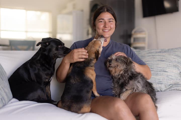 La Maile i els seus tres gossos seuen al sofà de l'allotjament a Airbnb.org.