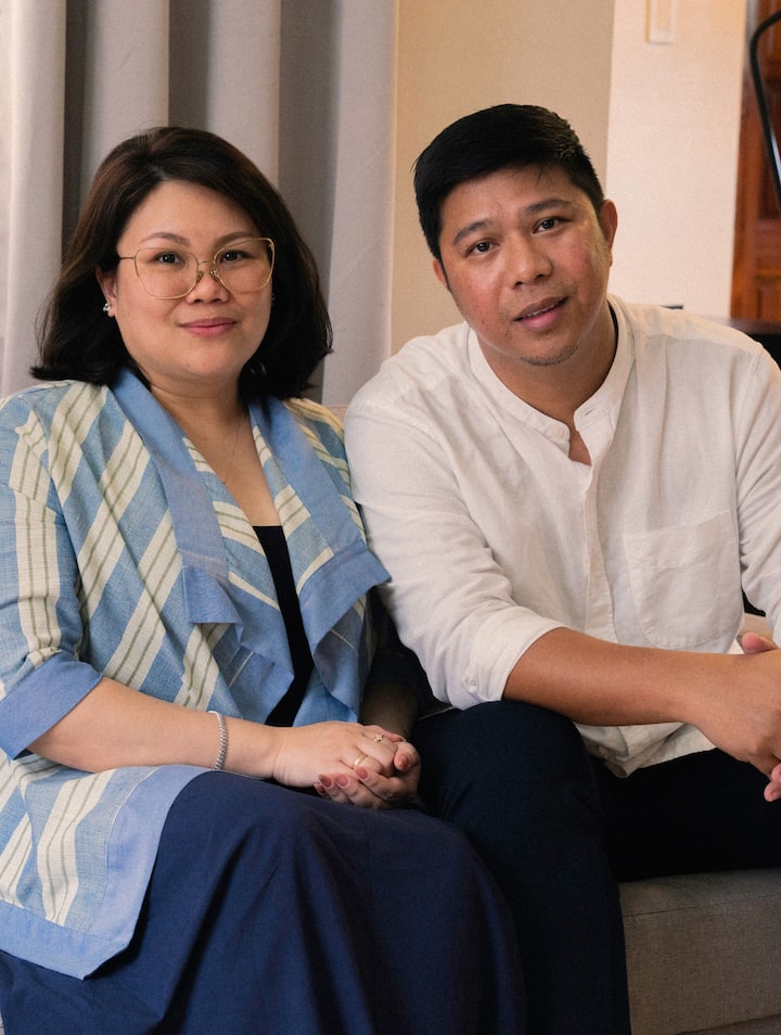 Two people seated together on steps outside, smiling toward the camera.