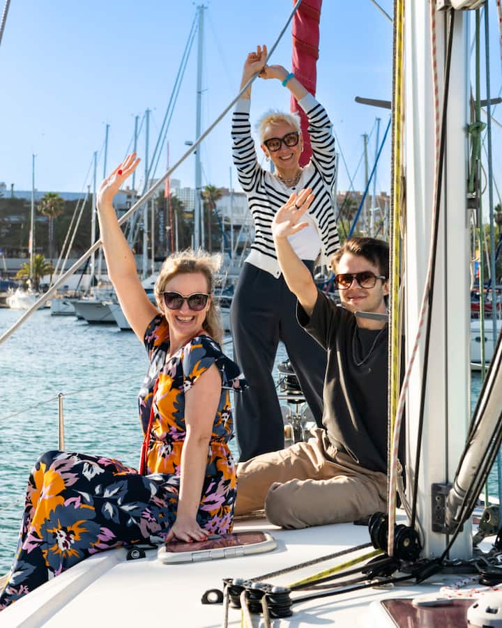 Un grupo de tres personas en un velero en Barcelona disfruta de unas vistas soleadas antes de la experiencia dedicada al eclipse.