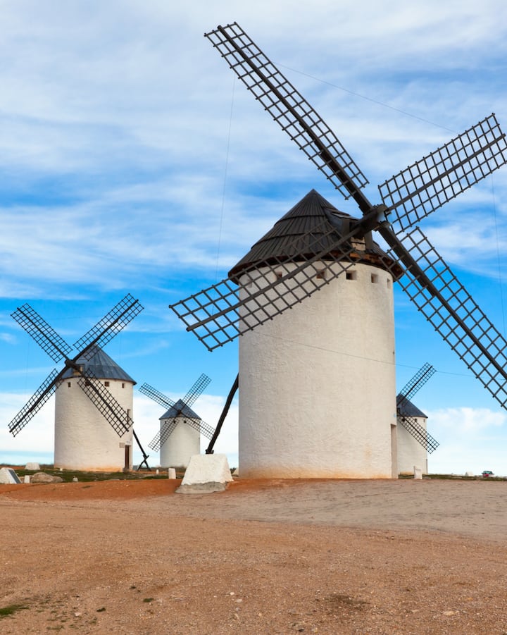 Una fila de históricos molinos de viento españoles en la cima de una colina. La imagen representa lugares pintorescos para ver el eclipse solar.