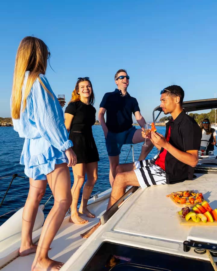 Un grupo de viajeros comparte aperitivos y bebidas en un yate frente a la costa de las islas Baleares para disfrutar de una experiencia sobre el eclipse.