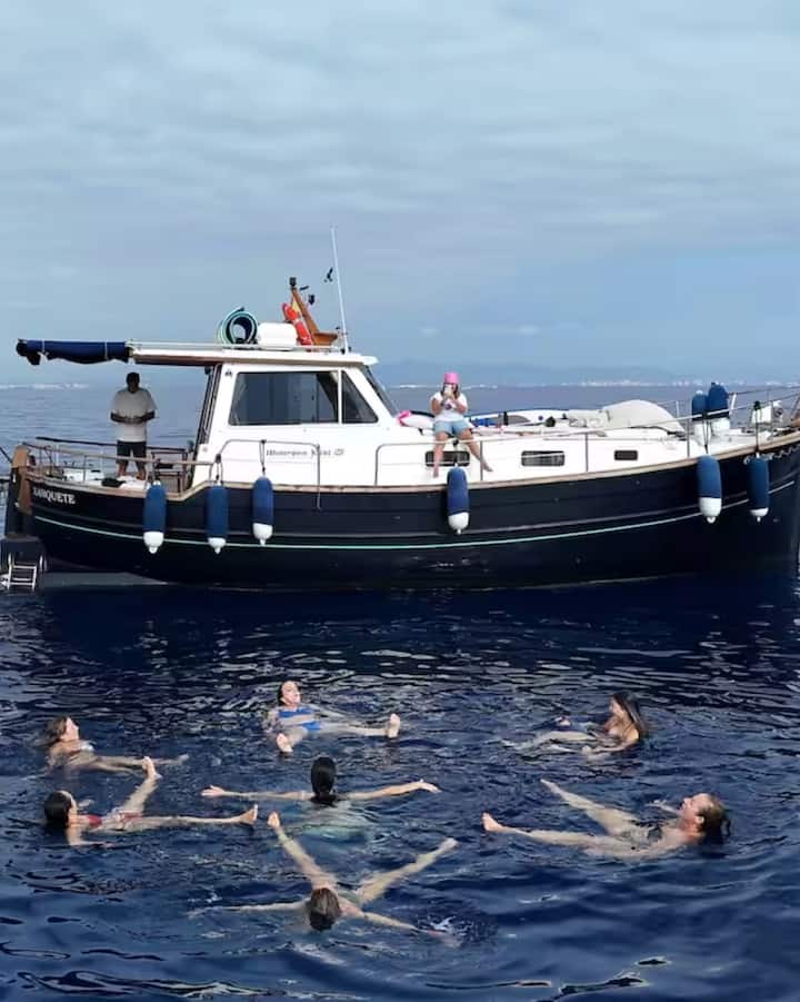 Un grupo de personas se relaja en una masa de agua junto a un barco anclado en una excursión para ver el eclipse en Valencia.