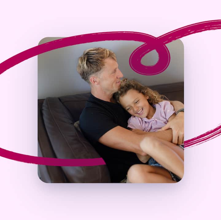 A father and daughter sitting together on a couch, laughing, with a hand drawn heart illustration framing the photo.