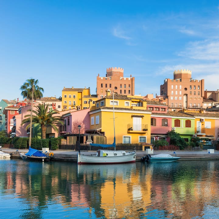 Barcos amarrados junto a casas de colores pastel a un paso del agua en Valencia. La imagen refleja la vida costera en el Mediterráneo.