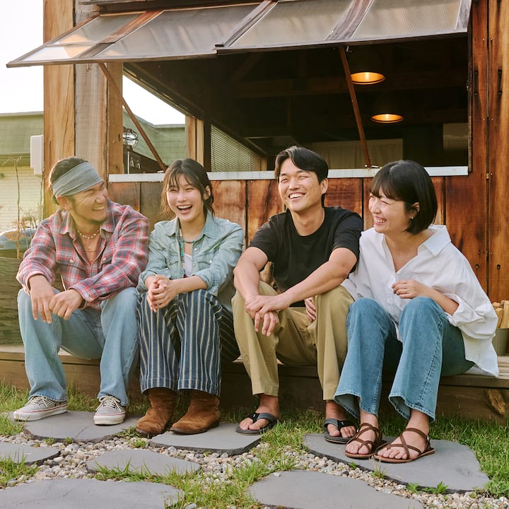 Airbnb 호스트 신윤수·신현주와 이웃들이 숙소 앞에 함께 앉아 웃으며 어울리는 모습