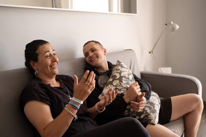 Žena i njen sin sjede na kauču, smiju se i smiješe.