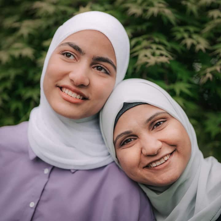 Two women in hijabs smiling together outdoors.