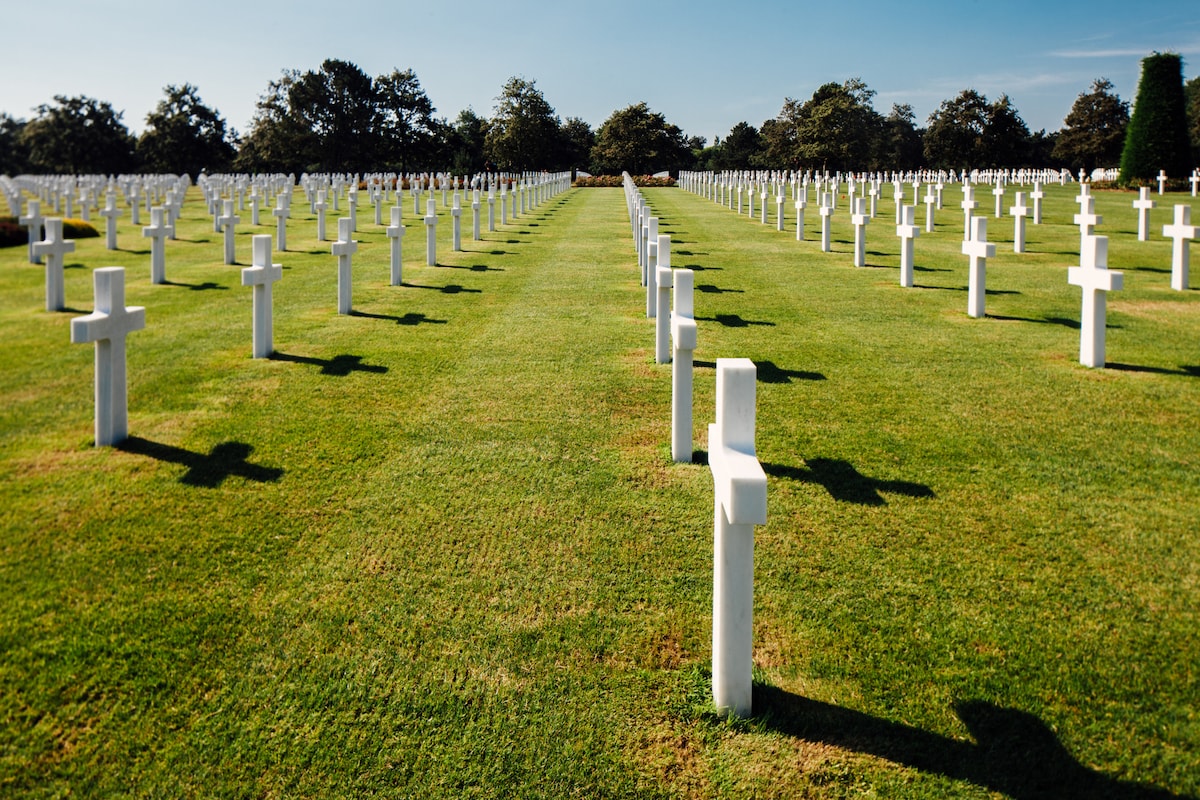 Rows of white crosses at a Normandy military cemetery under a clear blue sky.