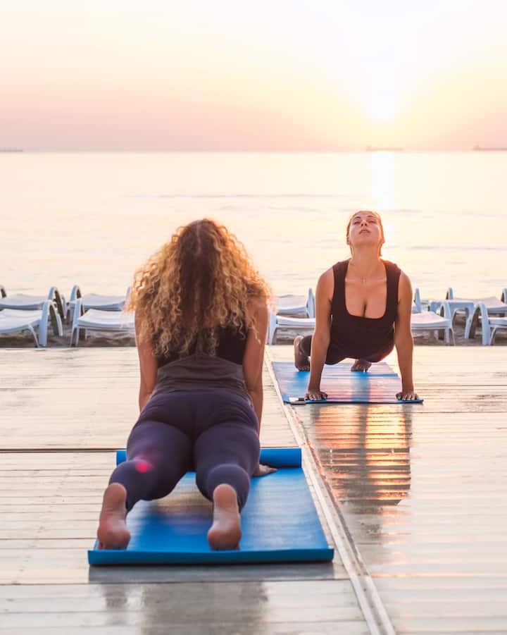 Varias personas hacen yoga sobre esterillas junto al paseo marítimo de Valencia para disfrutar del eclipse con una experiencia especial.