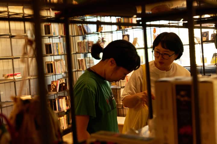 Seongbuk-dong host chatting with a guest inside a cozy book-filled space