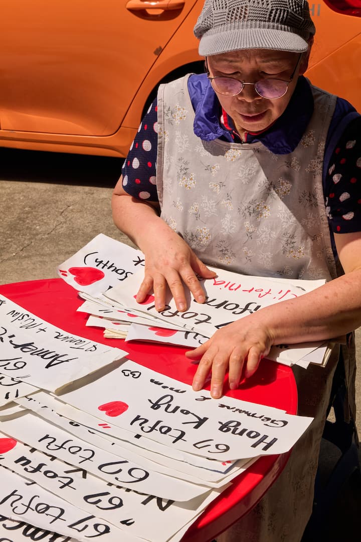Seongbuk-dong host arranging handwritten welcome notes with red hearts on a table in the sun.