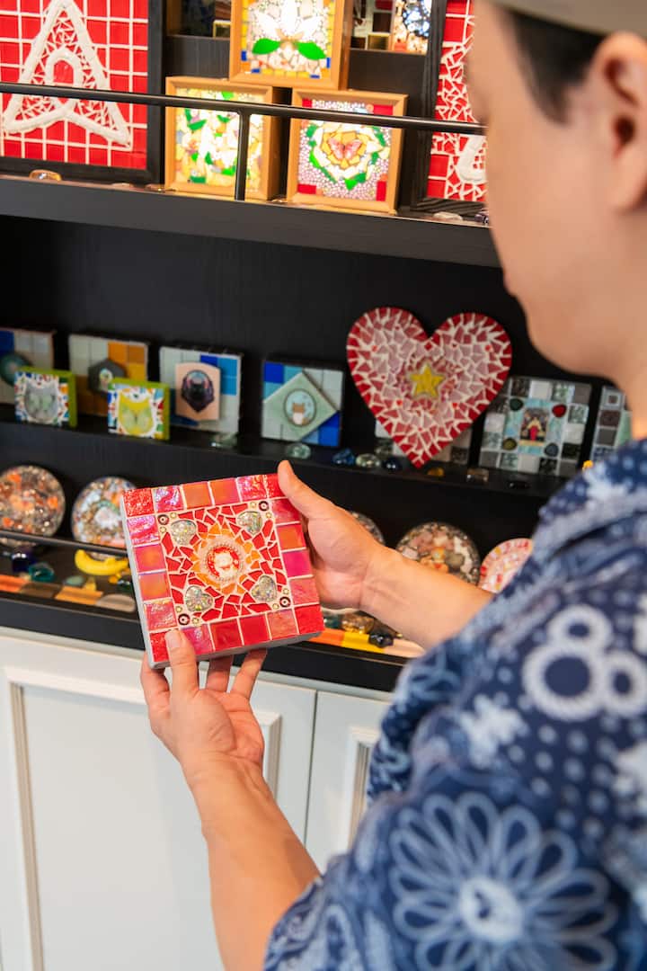 Close-up of artist presenting a handcrafted red mosaic tile