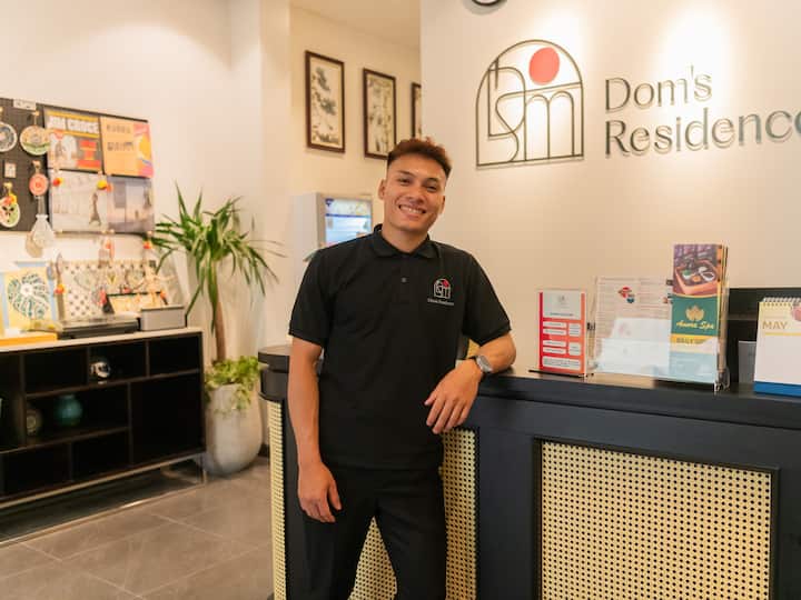 Dong smiles behind the front desk at Dom’s Residence, representing Khoi’s Airbnb hosting team in Vietnam.
