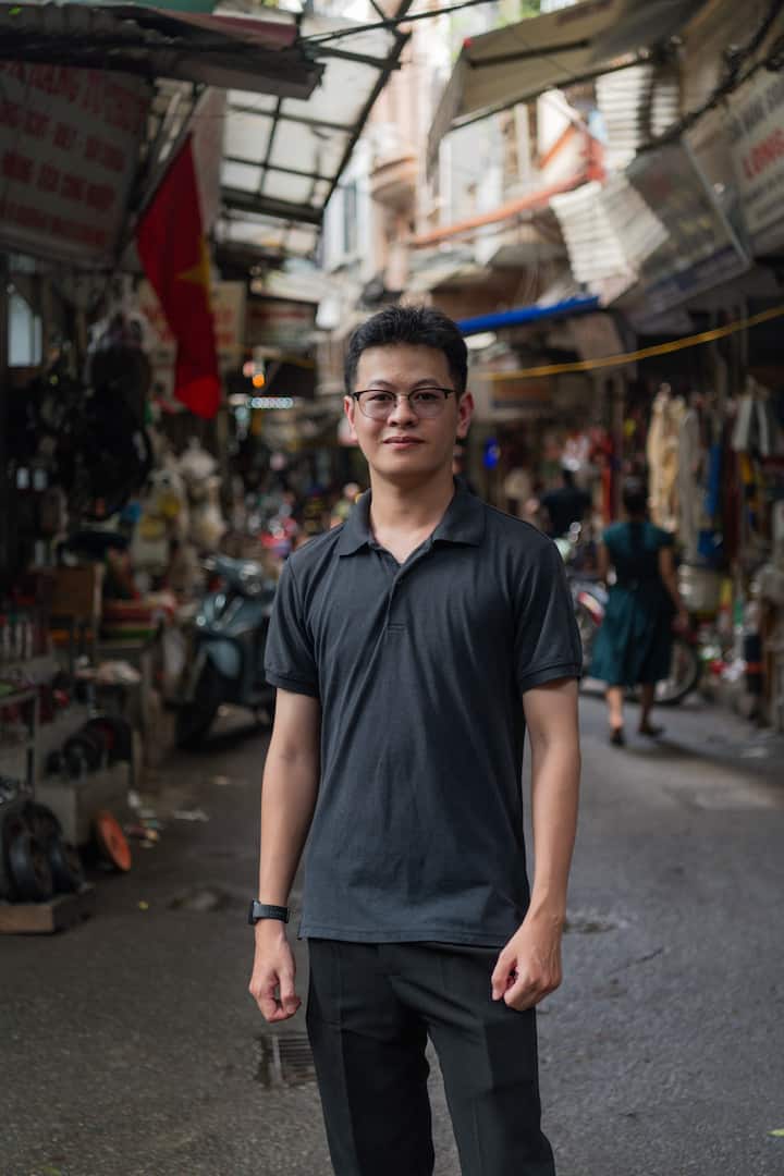 Quang poses in a vibrant Vietnam marketplace, highlighting his local Airbnb hosting story.