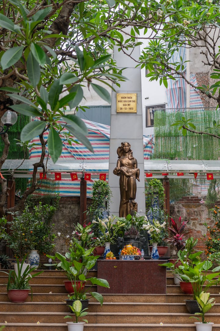 Memorial statue in Hà Nội surrounded by plants and offerings, featured in Quang’s Vietnam host story