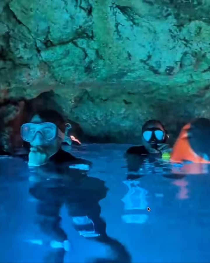Un grupo de personas que practican snorkel flotan en una cueva marina de un azul resplandeciente en las islas Baleares durante una escapada para ver el eclipse.