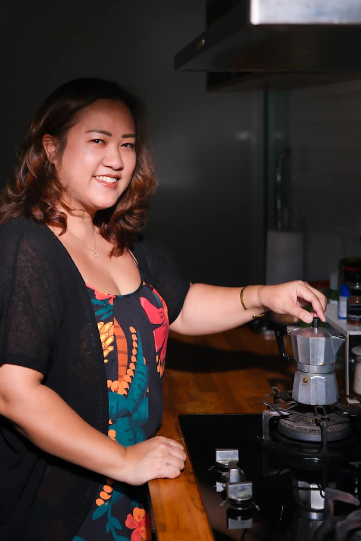 Host in a SEA kitchen smiling while brewing coffee on a stovetop for Airbnb.org guests