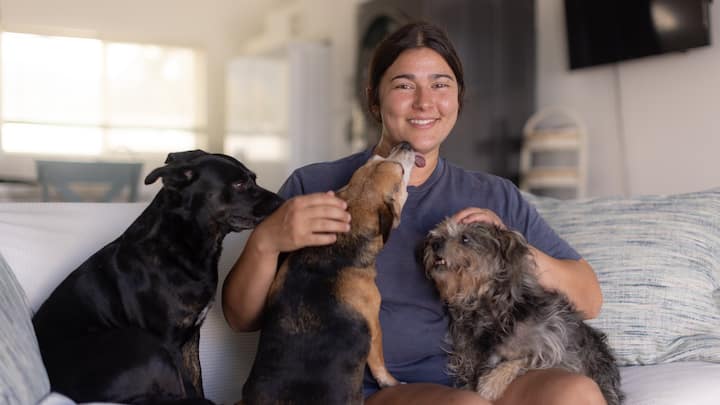 Woman and her three dogs sitting on the couch in their Airbnb.org stay.