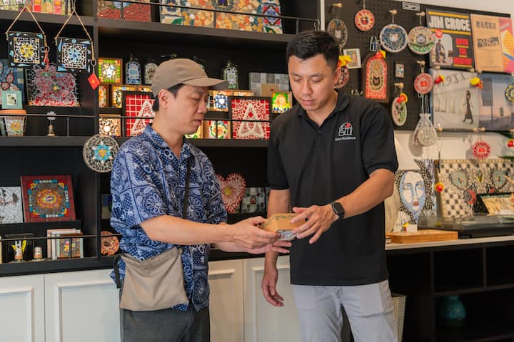 Khoi, a Vietnam host, discusses a small artisan piece with an artist