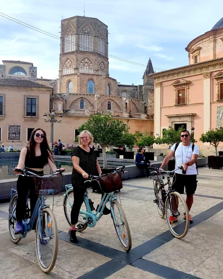 Unos ciclistas hacen una pausa en una soleada plaza de Valencia. La imagen representa una forma local de disfrutar del eclipse.