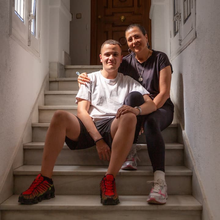 Two people, a mother and her son, sitting on the steps up to their Airbnb.org stay.