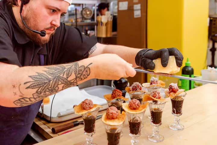 Chef leading an Airbnb Experience at Grand Central Market, plating small meatball dishes in Downtown Los Angeles