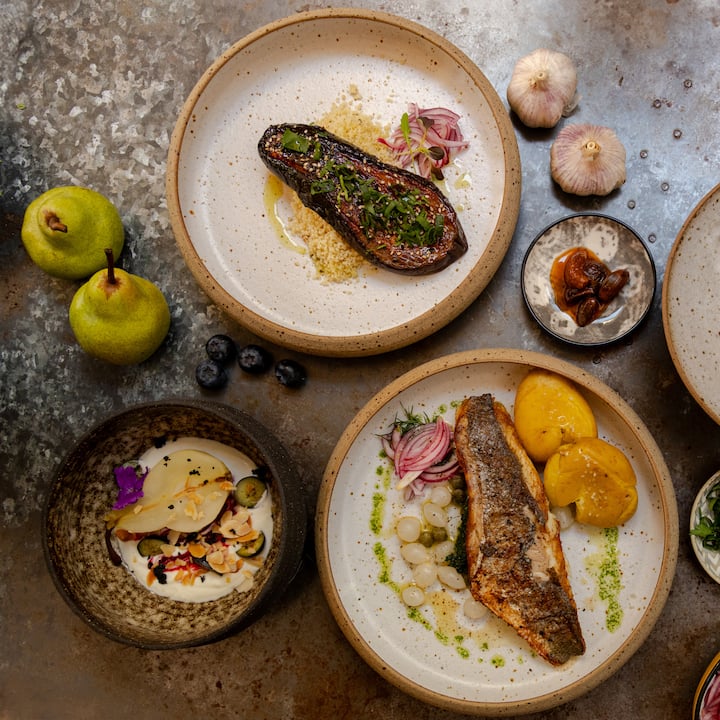 Chef-prepared plates of roasted fish and vegetables arranged on a table, showcasing an elegant meal service.