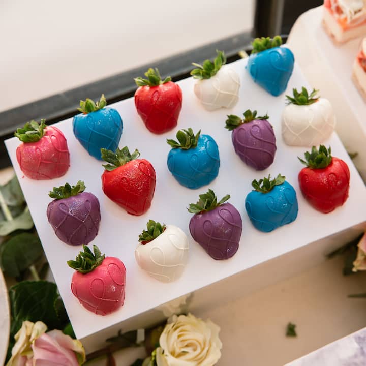 Colorful chocolate-dipped strawberries neatly arranged on a display stand for a catered event.