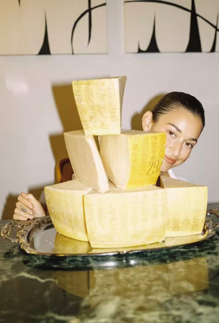 Guest in New York City smiling behind a stack of Parmigiano Reggiano wedges on a silver tray