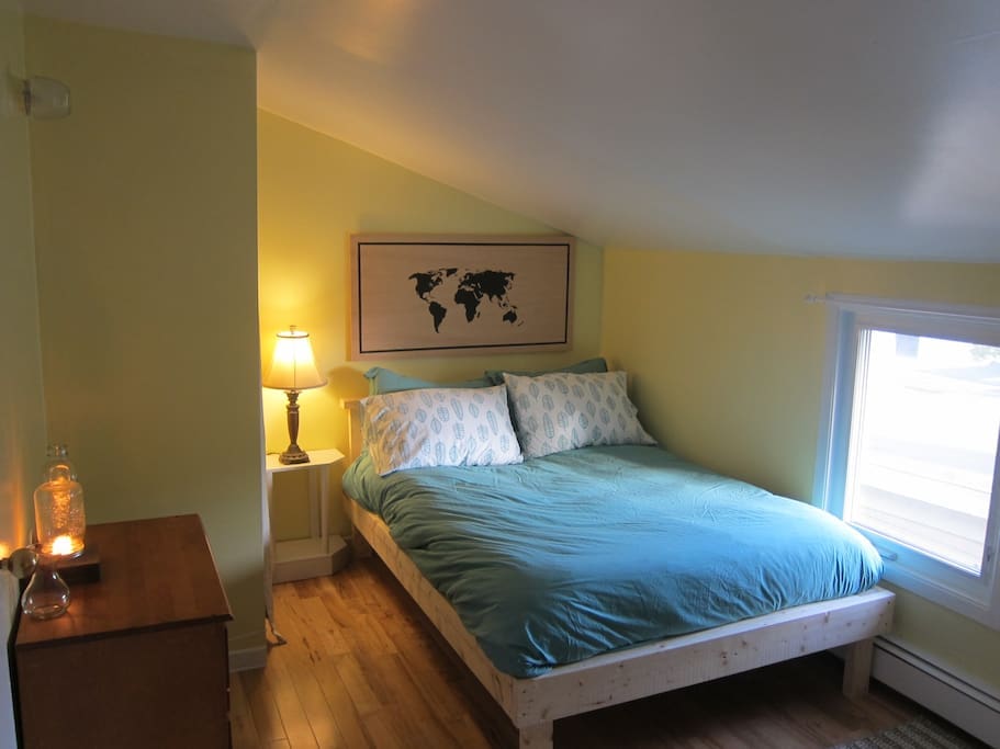The bedroom has a cozy double bed with feather duvet, dresser, closet and homemade map art!