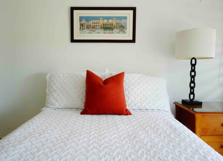 חדר שינה בקומה השנייה עם מיטה ושולחן עבודה מלאים.