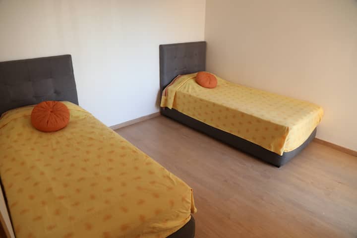 Chumba cha pili cha kulala kinatoa vitanda viwili vya starehe vinavyoangalia mwonekano mzuri wa bwawa lililozungukwa na sehemu za kijani kibichi 