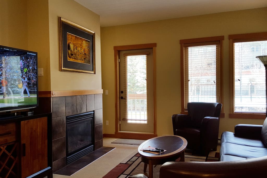 Living area with 60" Smart TV, sofa bed, coffee table, fireplace, and access to deck