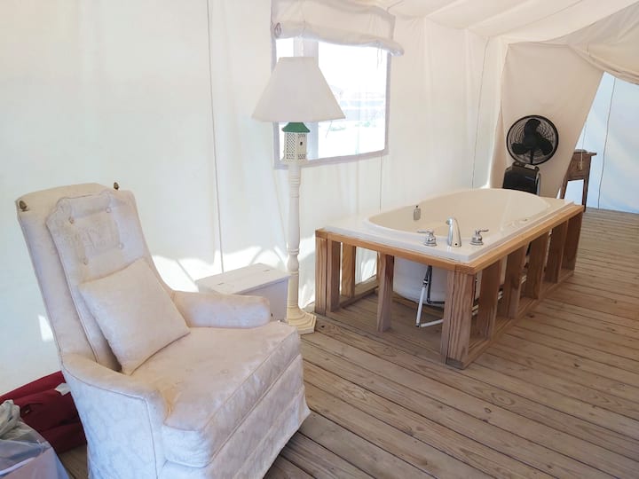 Mwonekano wa ndani wa Nyumba ya Mbao ya Kifahari ya Canvas #1 @ The Silverlaken Estate kutoka kwenye ukumbi.  Imewekewa beseni la jakuzi, magodoro 2 ya kifalme,
, friji ndogo, feni inayoweza kubebeka, kiti cha AC na sofa. Ina bafu kubwa. Jiko la nje la pamoja.