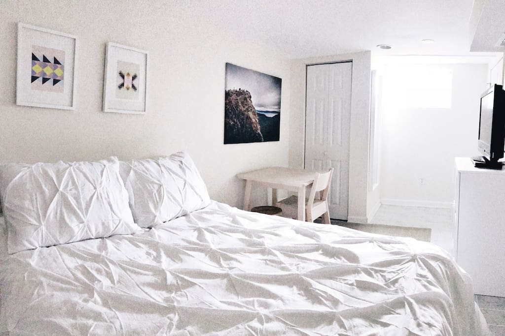 Bright, spacious basement bedroom with queen-sized bed, table and chairs, and TV with Netflix and Amazon Prime streaming provided.