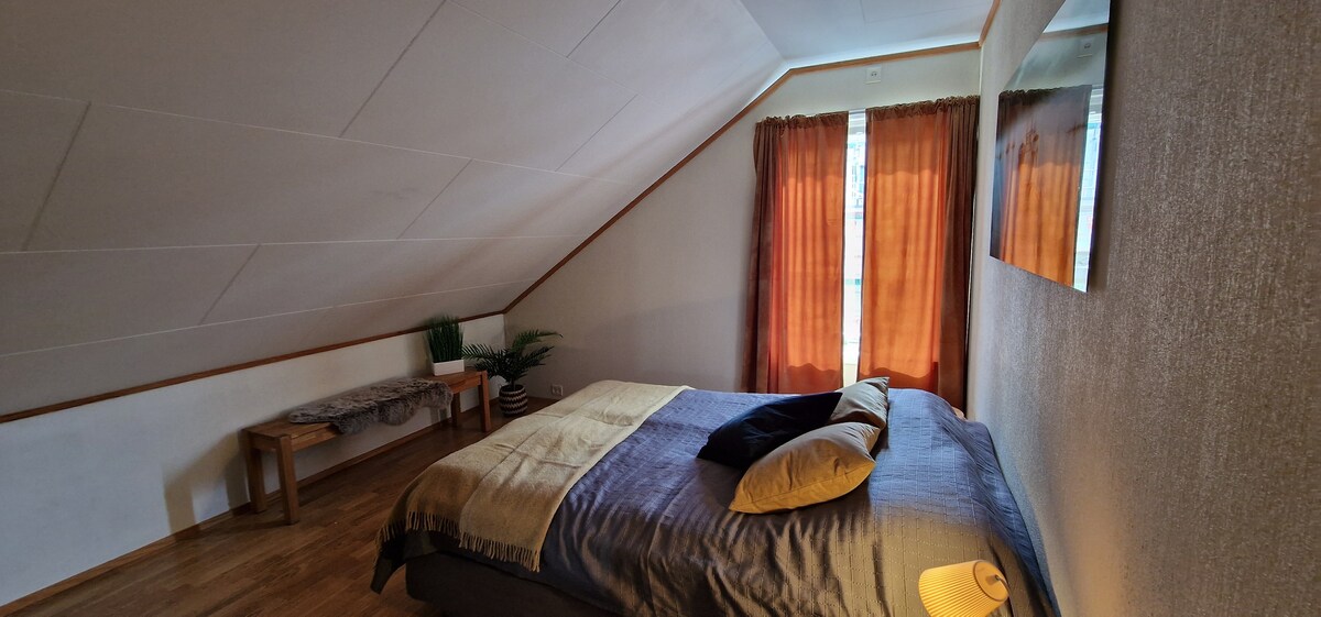 חדר שינה עם מיטה זוגית ושולחן כתיבה וארון בגדים. 