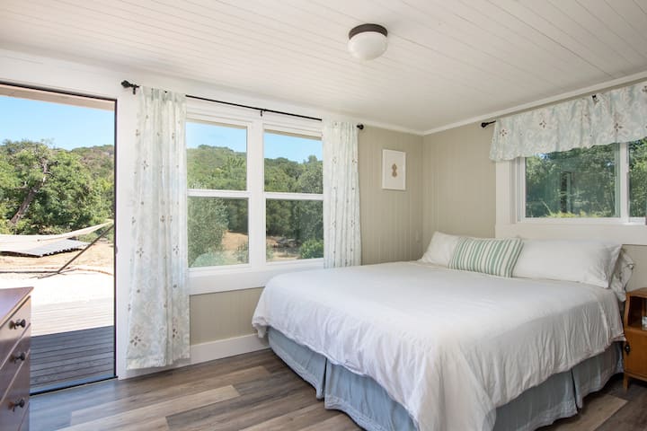 Back cottage California King bedroom with views of the valley. Your own private entrance leads to the back deck and seating area where you may access the attached game room or walk along the flagstone path to the main house.  