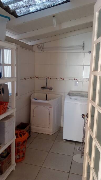 Lavanderia com tanque e naquina de lavar. Casa com varal na area externa.